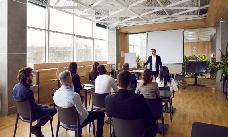 Rear view of a team of people having class with trainer regarding Software Training Franchise Opportunities.