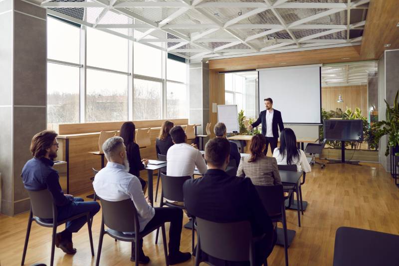 Rear view of a team of people having class with trainer regarding Software Training Franchise Opportunities.